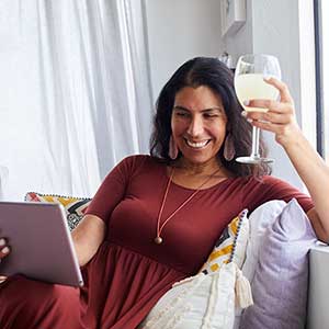 Une femme souriante chez elle qui discute avec un ami sur vidéo.